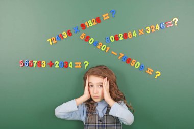 Kız bir yeşil okul yönetimi mıknatıslar yeşil zemin üzerine düşüncelerini tasvir sayıların önünde duruyor