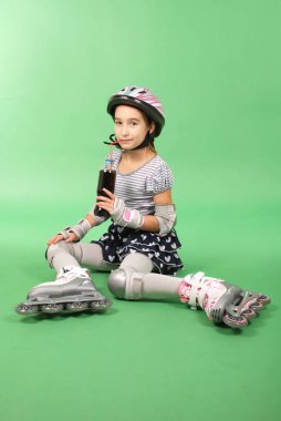 Yeşil arka plan ve içecek kola üzerinde yalan rollerskates güzel kız