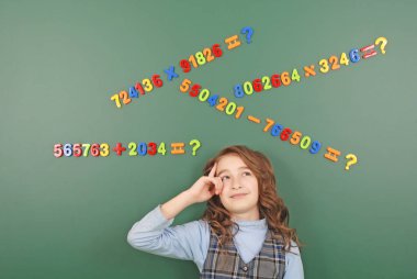 Kız bir yeşil okul yönetimi mıknatıslar yeşil zemin üzerine düşüncelerini tasvir sayıların önünde duruyor