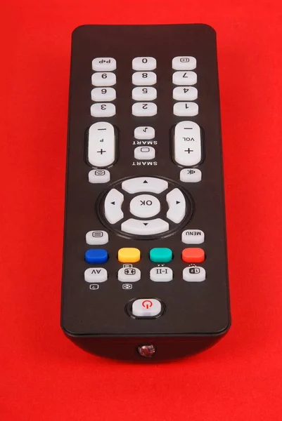 在红色背景上被隔绝的电视的黑色遥控器 — 图库照片
