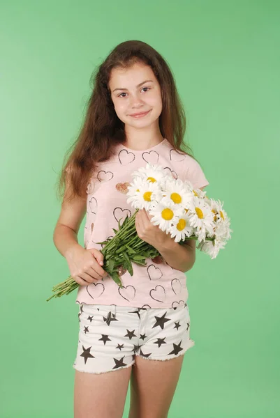 一个年轻的女孩与一束 Chamomiles 的肖像 在绿色背景上隔离 — 图库照片