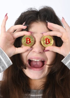 Güzel kız göz yerine iki altın cryptocurrency bitcoin beyaz arka plan üzerinde elinde tutar. Bitcoin kavramı içinde fiyat düşüyor