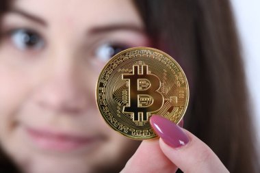 Güzel kız onun önünde tutan yeni altın cryptocurrency bitcoin beyaz arka plan üzerinde eller. Yumuşak odak