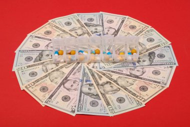 İzole kırmızı zemin üzerine bir daire şeklinde para açık kutusunda renkli kapsül