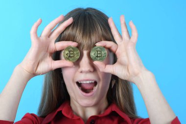Güzel kadın yerine iki altın cryptocurrency elinde Bitcoin göz tutar