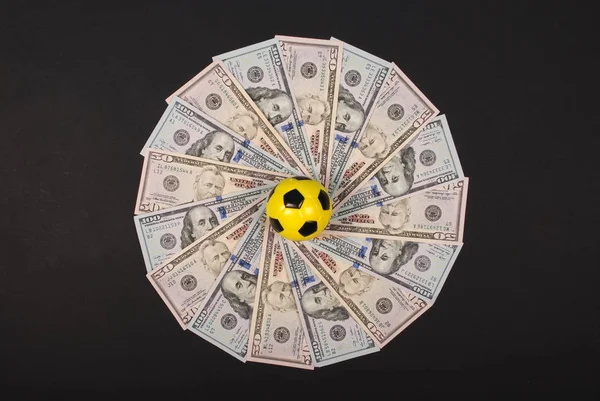 Fußball kleine Kugel auf Mandala Kaleidoskop aus Geld liegend. Geld und Fußball - Sport und Wirtschaft. — Stockfoto