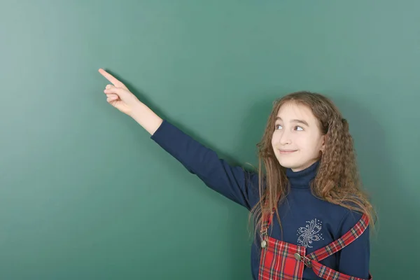 Uczennica w pobliżu zielonej szkoły zarządu. Młoda Dziewczyna zabawy trzyma kredę w ręku. — Zdjęcie stockowe