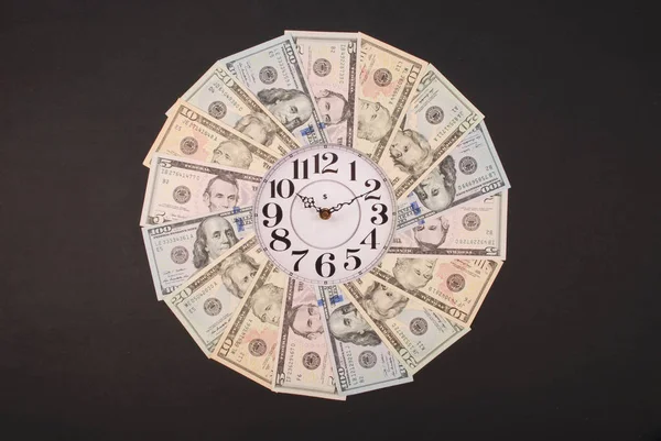Η έννοια του ρολογιού και του δολαρίου. Ρολόι στο Καλειδοσκόπιο μάνταλα από χρήματα. Αφηρημένα χρήματα φόντο πλέγμα μοτίβο επαναλαμβάνεται κύκλος μάνταλα. — Φωτογραφία Αρχείου