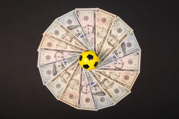 Fußball kleine Kugel auf Mandala Kaleidoskop aus Geld liegend. Geld und Fußball - Sport und Wirtschaft. — Stockfoto