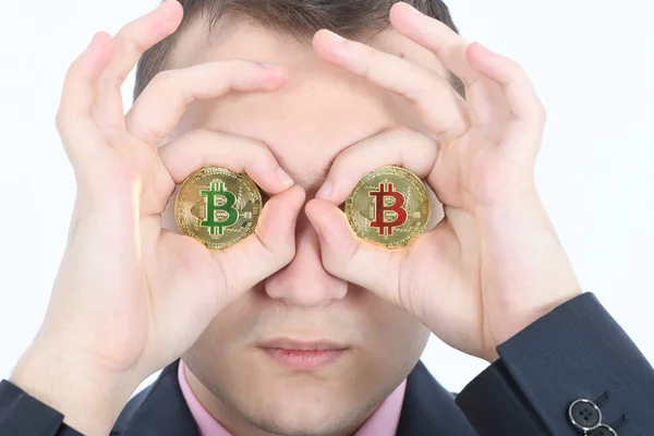 El hombre mantiene el ojo en su lugar dos bitcoin criptomoneda de oro en las manos — Foto de Stock