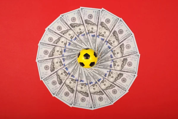 Футбольный мячик лежит на мандале калейдоскопа из денег. Деньги и футбольный мяч - спорт и бизнес . — стоковое фото