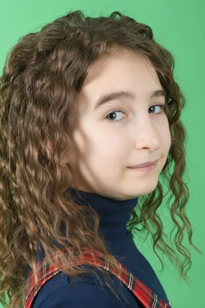 Retrato de adorable colegiala sonriente con el pelo rizado de pie aislado en un verde — Foto de Stock