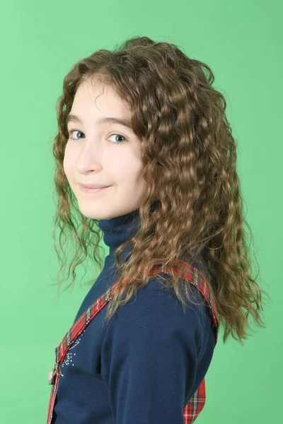 Portret urocza uśmiechnięta uczennica z curl włosy stojący izolowane na zielonym — Zdjęcie stockowe