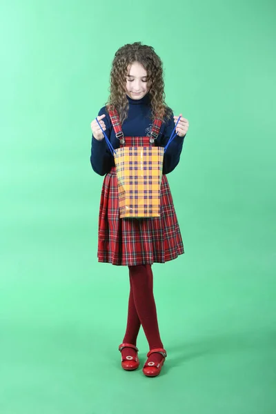 Niño con una textura a cuadros de embalaje amarillo aislado sobre fondo verde. Regalo de vacaciones, compras . — Foto de Stock