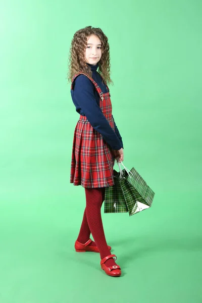 Child with a green packaging checkered texture isolated on green background. Girl likes shopping on sale season. Holiday present, shopping.