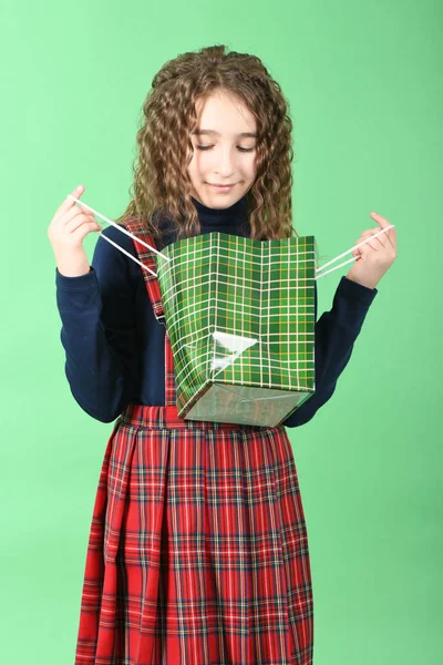 Дитина з зеленою упаковкою картатої текстури ізольована на зеленому тлі. Дівчині подобаються покупки в сезон продажу. Святковий подарунок, покупки . — стокове фото