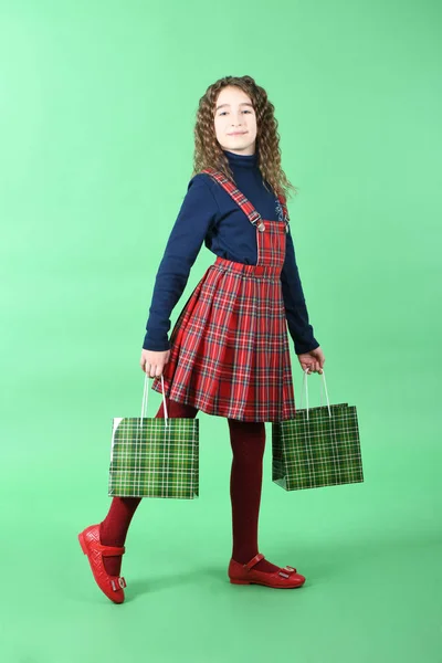 Niño con una textura a cuadros de embalaje verde aislado sobre fondo verde. Chica le gusta ir de compras en temporada de venta. Regalo de vacaciones, compras . — Foto de Stock