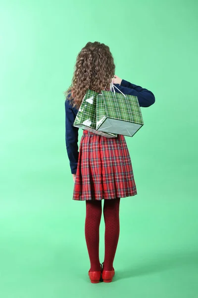 Дитина з зеленою упаковкою картатої текстури ізольована на зеленому тлі. Дівчині подобаються покупки в сезон продажу. Святковий подарунок, покупки . — стокове фото