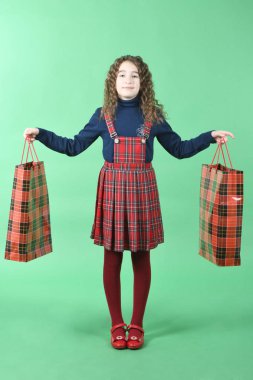 Yeşil arka planda yalıtılmış kırmızı bir paket olan çocuk. Küçük güzellik alışverişkolik. Tatil hediyesi, alışveriş. 