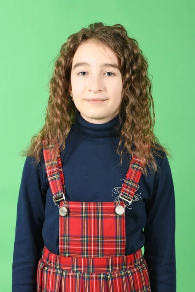 Retrato de adorable colegiala sonriente con el pelo rizado de pie aislado en un verde — Foto de Stock