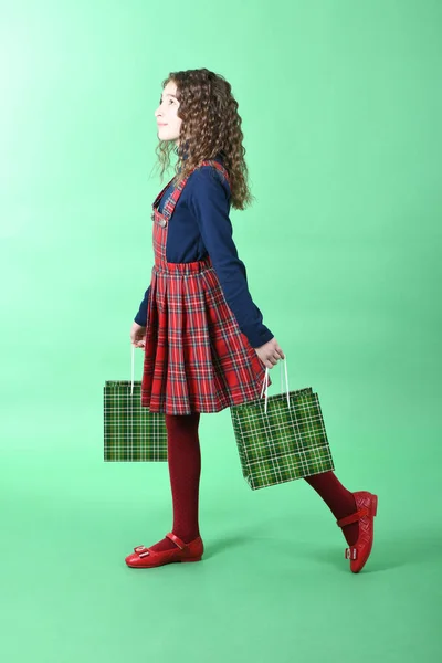 Niño con una textura a cuadros de embalaje verde aislado sobre fondo verde. Chica le gusta ir de compras en temporada de venta. Regalo de vacaciones, compras . — Foto de Stock