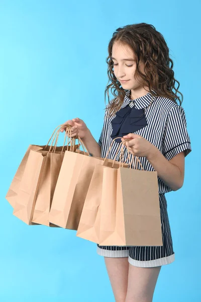 Criança com um pacote isolado no fundo azul. Presente de férias, compras. Criança feliz compras no shopping . — Fotografia de Stock