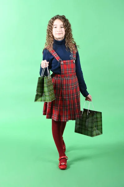 Kind mit grüner Verpackung und karierter Textur auf grünem Hintergrund. Mädchen mag Einkaufen im Verkauf Saison. Weihnachtsgeschenk, Einkaufen. — Stockfoto