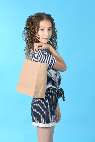 Bambino con un pacchetto isolato su sfondo blu. Regalo di festa, shopping. Ragazzo felice shopping nel centro commerciale . — Foto Stock