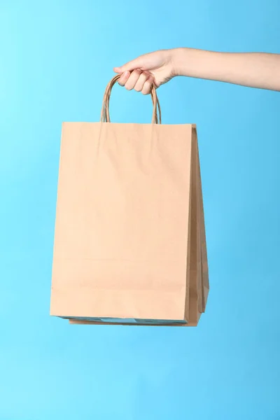 Criança mão segurando sacos de compras de papel isolado no fundo azul . — Fotografia de Stock