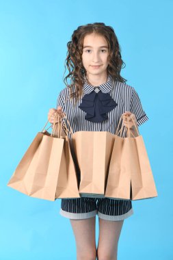 Mavi arka planda izole edilmiş bir paketolan çocuk. Tatil hediyesi, alışveriş. Alışveriş merkezinde çocuk mutlu alışveriş. 