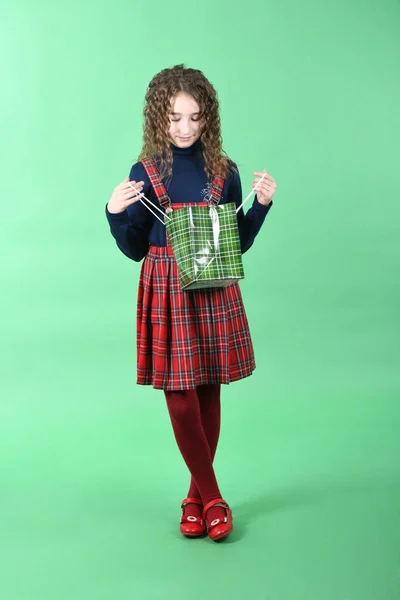 Niño con una textura a cuadros de embalaje verde aislado sobre fondo verde. Chica le gusta ir de compras en temporada de venta. Regalo de vacaciones, compras . — Foto de Stock