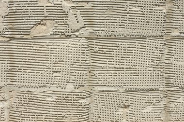 Duvardaki eski fayans yapıştırıcısının arka planı tamir ediliyor. Çentikli malanın soyut deseni. Yüksek çözünürlüklü. Tam alan derinliği (DOF).