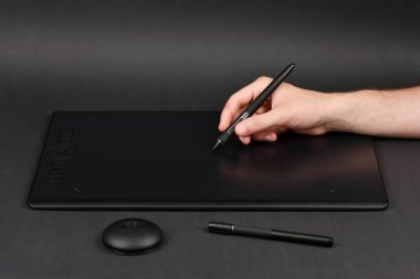 Tabletinde kalem olan tasarımcının eli. Siyah arka planda izole edilmiş. Yüksek çözünürlüklü. Tam alan derinliği.