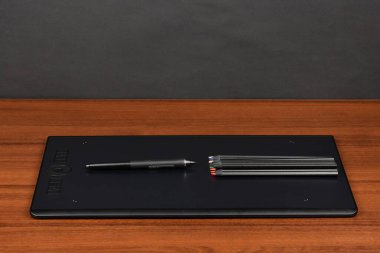 Profesyonel grafik tableti, dijitalleştirilmiş ve ahşap masa üzerinde çok renkli kalemler. Yüksek çözünürlüklü. Tam alan derinliği