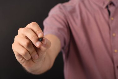 Erkek eli siyah arkaplanda izole edilmiş bir kalem tutar. Yüksek çözünürlüklü fotoğraf.