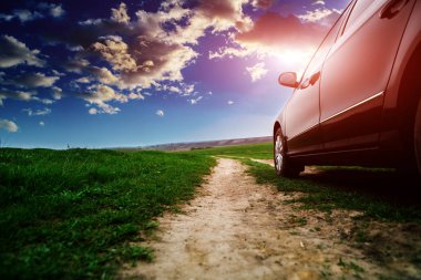 güneşli yeşil alan boyunca toprak yolda araba 