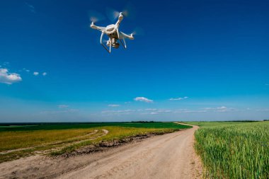 yeşil alanın üzerine mavi gökyüzünde uçan quadcopter dron