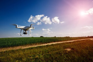 yeşil alanın üzerine mavi gökyüzünde uçan quadcopter dron