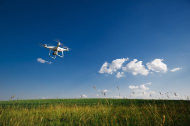 yeşil alanın üzerine mavi gökyüzünde uçan quadcopter dron