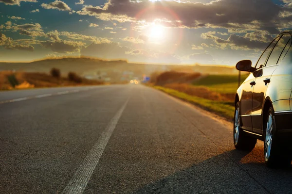 black car on asphalt road in summer, sunset sky