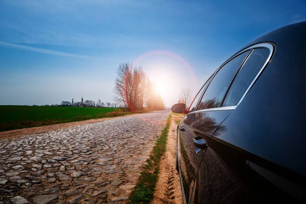 black car on asphalt road in summer, sunset sky