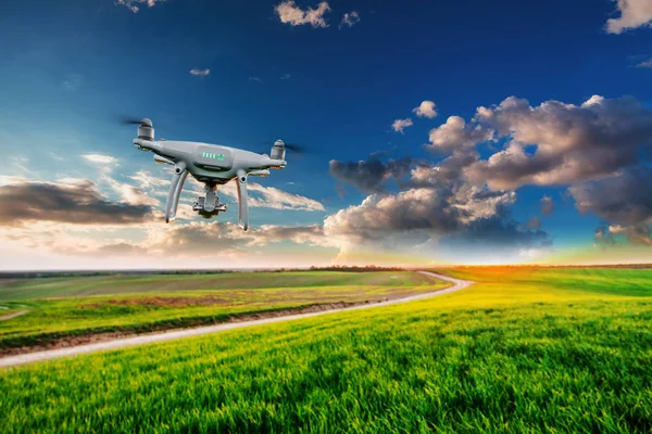 quadcopter drone flying in blue sky over green field