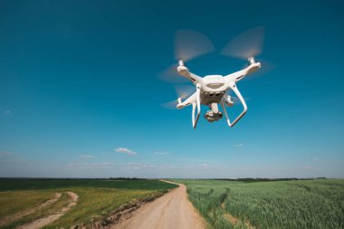 yeşil alanın üzerine mavi gökyüzünde uçan quadcopter dron