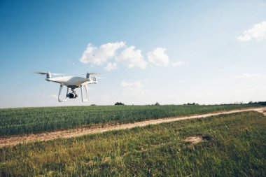 yeşil alanın üzerine mavi gökyüzünde uçan quadcopter dron