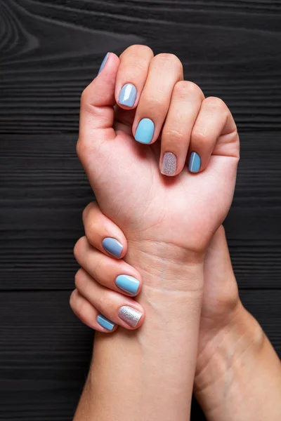 Mani Femminili Con Manicure Colori Blu Argento Sfondo Nero Legno — Foto Stock