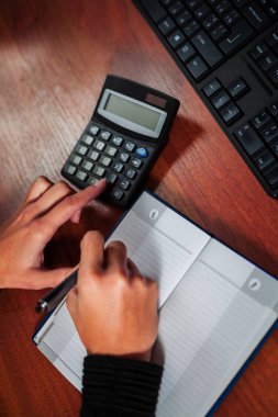 Not Defteri'nde yazma ve ahşap masaüstü hesap makinesi sayma kız