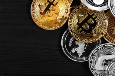 Ahşap zemin üzerinde bitcoin, dalgalanma ve ethereum sembollü gümüş ve altın sikkeler.