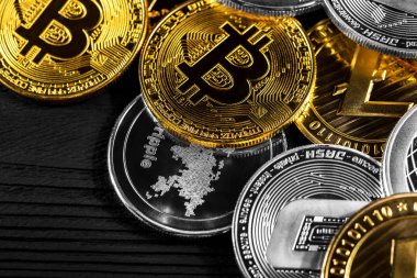 Ahşap zemin üzerinde bitcoin, dalgalanma ve ethereum sembollü gümüş ve altın sikkeler.