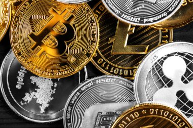 Ahşap zemin üzerinde bitcoin, dalgalanma ve ethereum sembollü gümüş ve altın sikkeler.