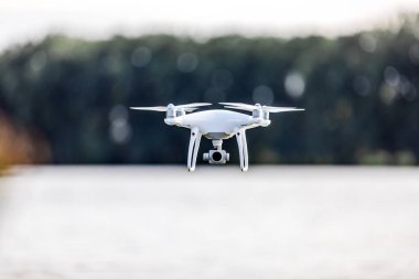 bir kamera ile bir göl üzerinde uçan quadcopter dron.